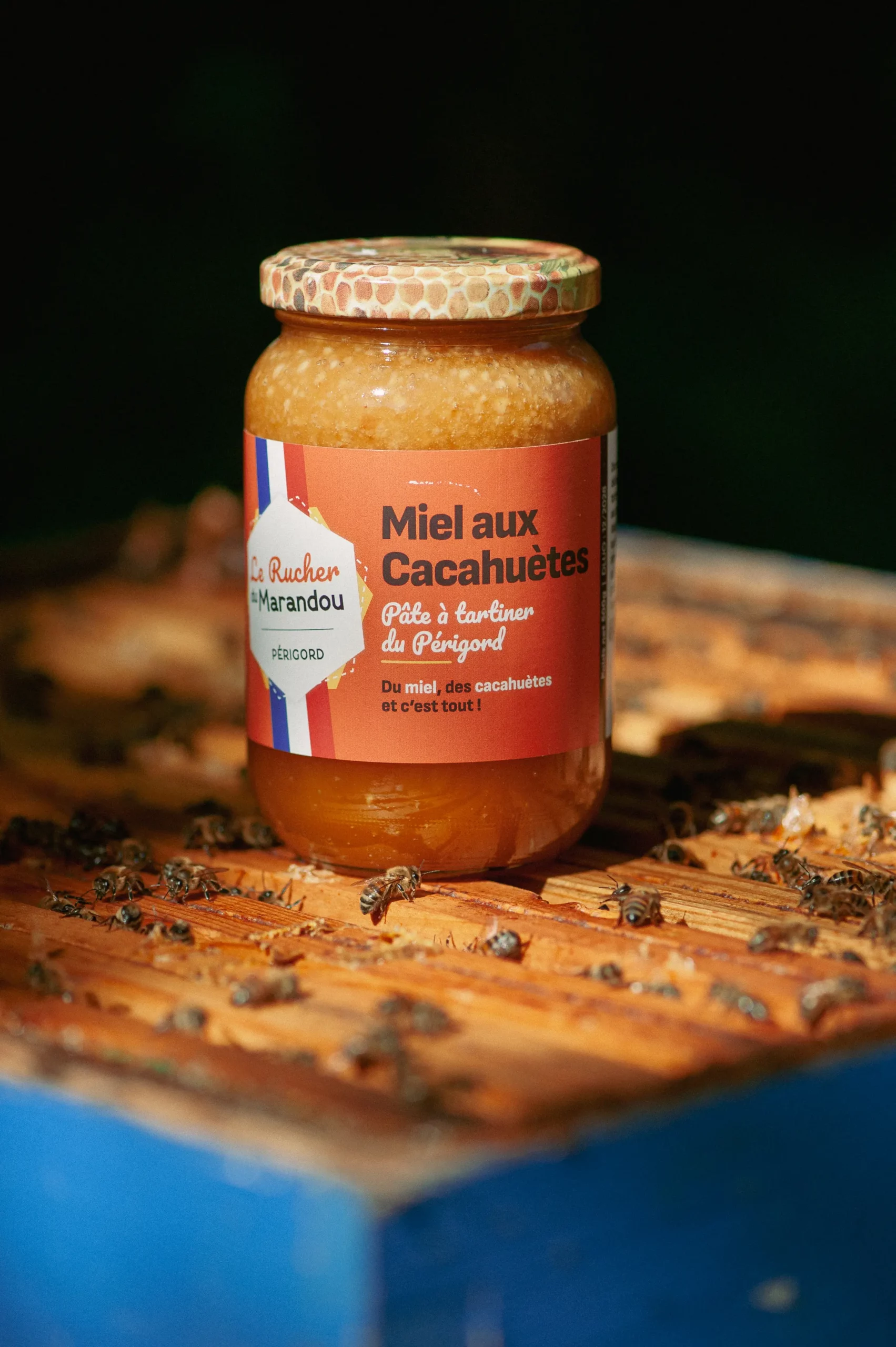 Pot de miel aux cacahuètes 500 g du Périgord posé sur une ruche avec les abeilles – Rucher du Marandou