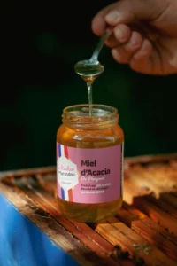 Pot de miel artisanal du Périgord posé sur une ruche avec des abeilles – Rucher du Marandou